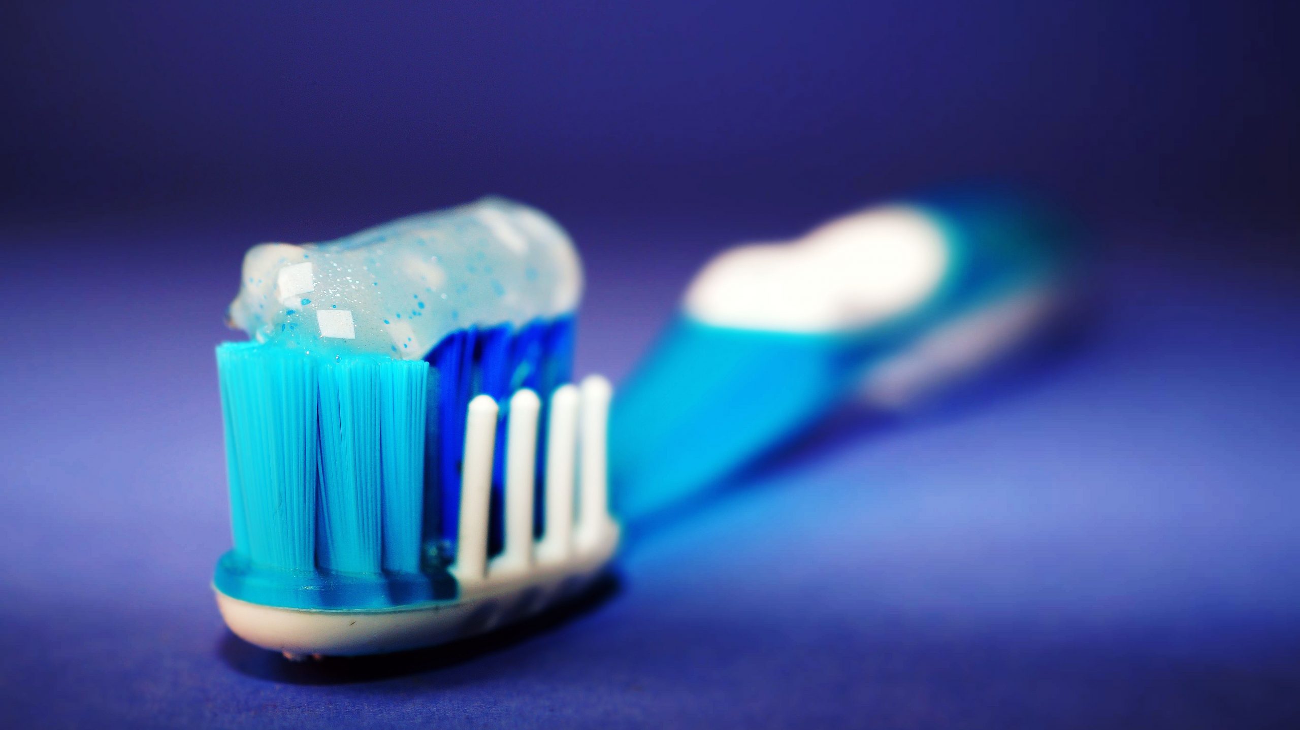 Macro shot of a toothbrush with blue toothpaste and blurred background